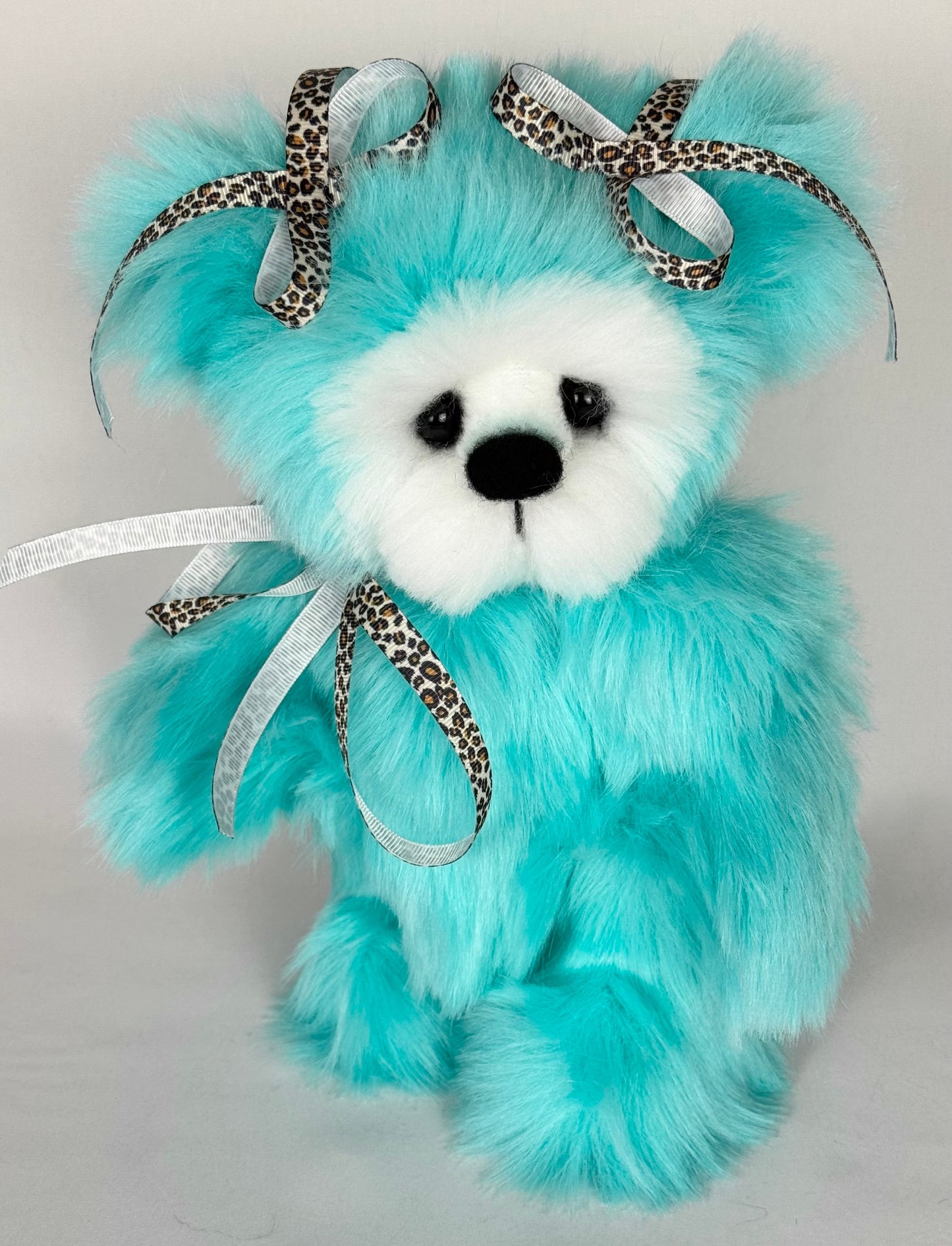 Gros plan sur l’ourse Safari, peluche de collection avec rubans léopard, poils longs et doux, yeux en verre noir et finition haut de gamme – objet décoratif non destiné aux enfants.