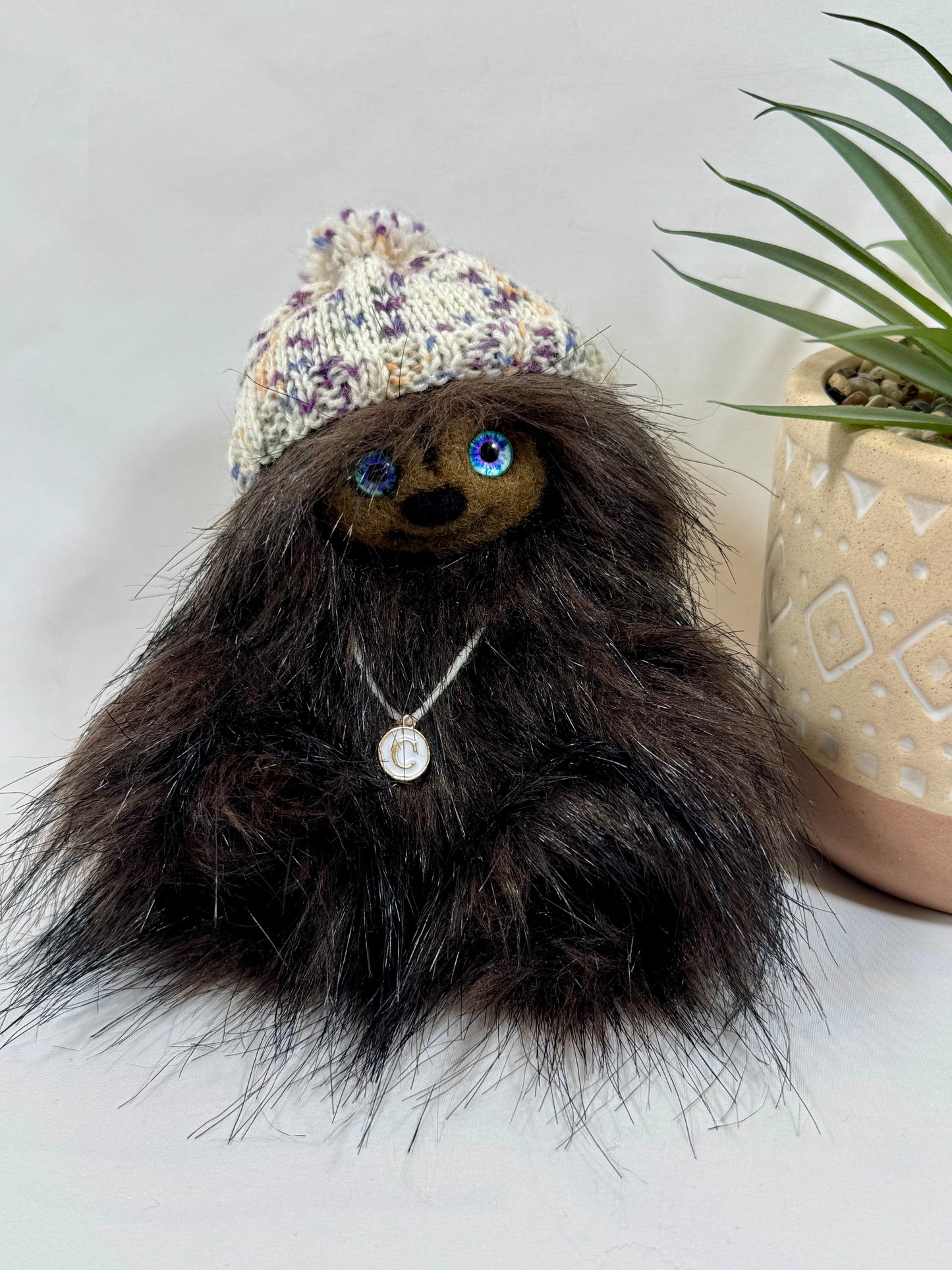 Détail du visage de Châtaigne, peluche artisanale aux yeux en verre bleus et sourire doux