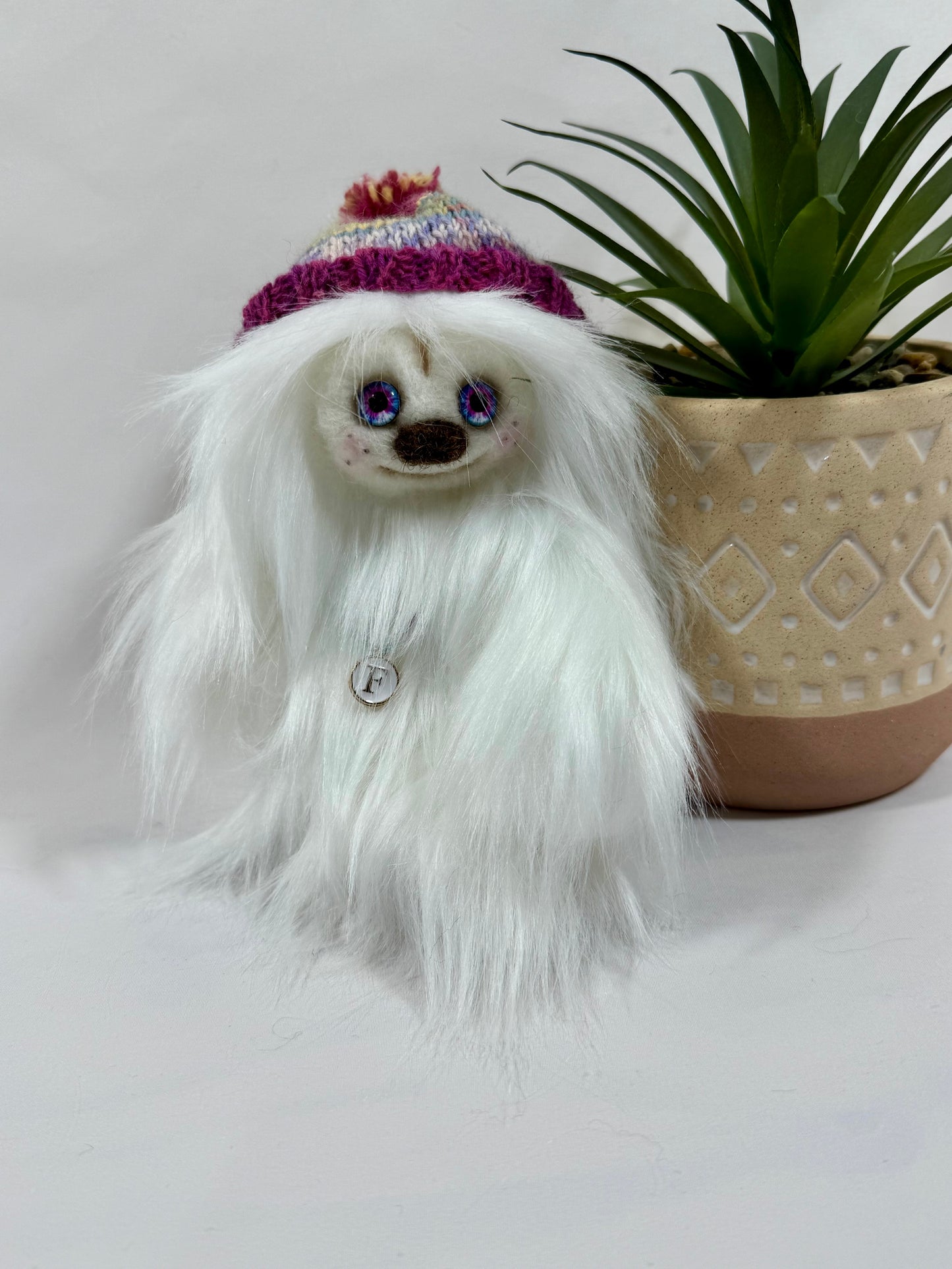 Détail du visage de Flocon, peluche artisanale aux yeux en verre bleu et rose et nez feutré à l’aiguille