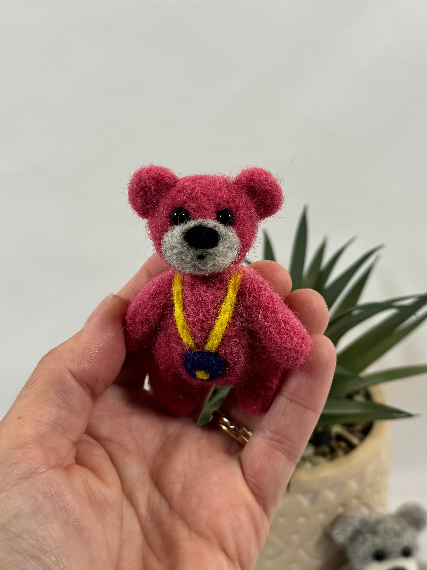 Mini ours feutré rose 9 cm avec collier jaune et violet – création artisanale