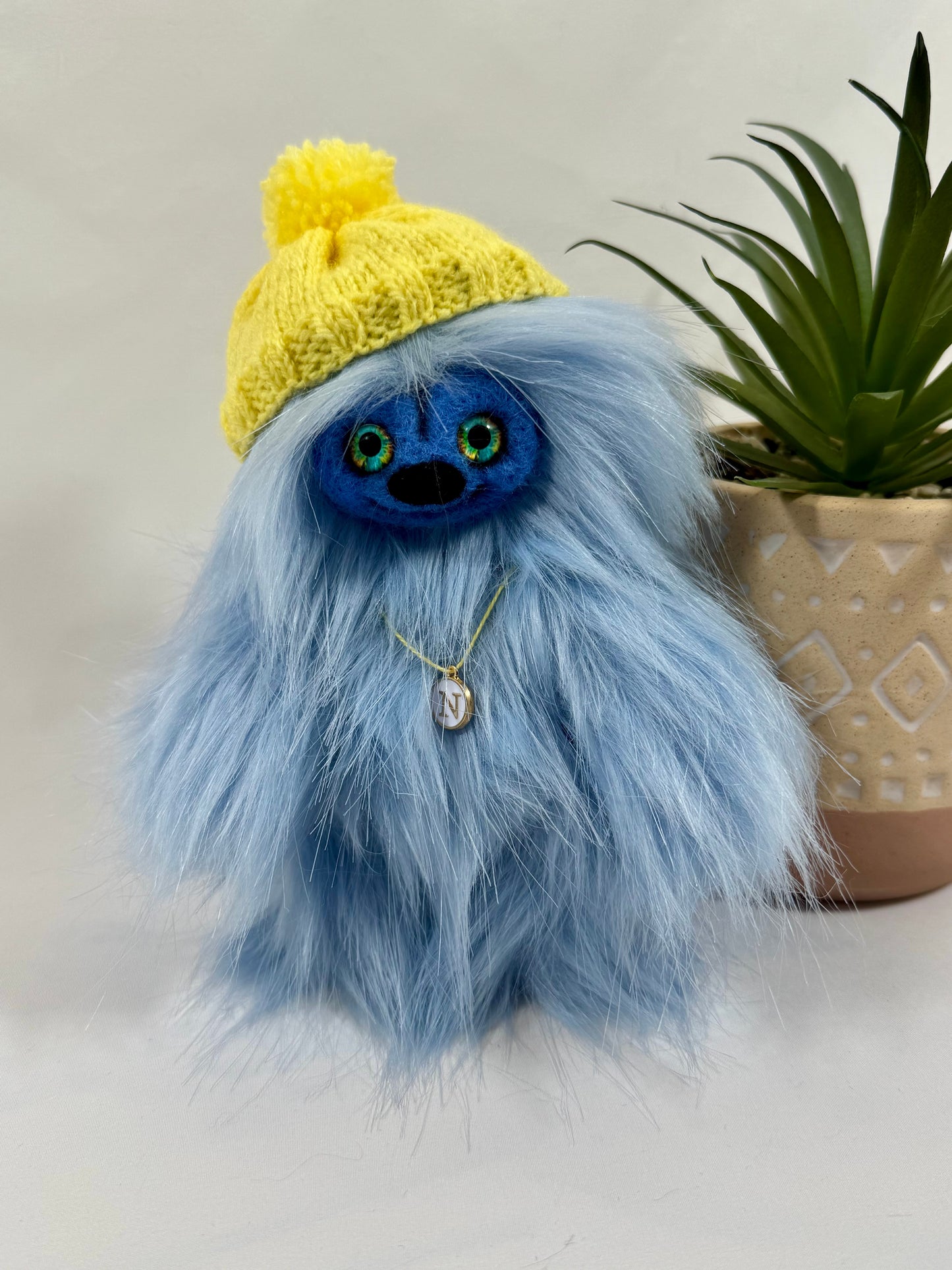 Détail du visage de Nemo, peluche artisanale aux yeux en verre bleu et jaune et nez feutré noir