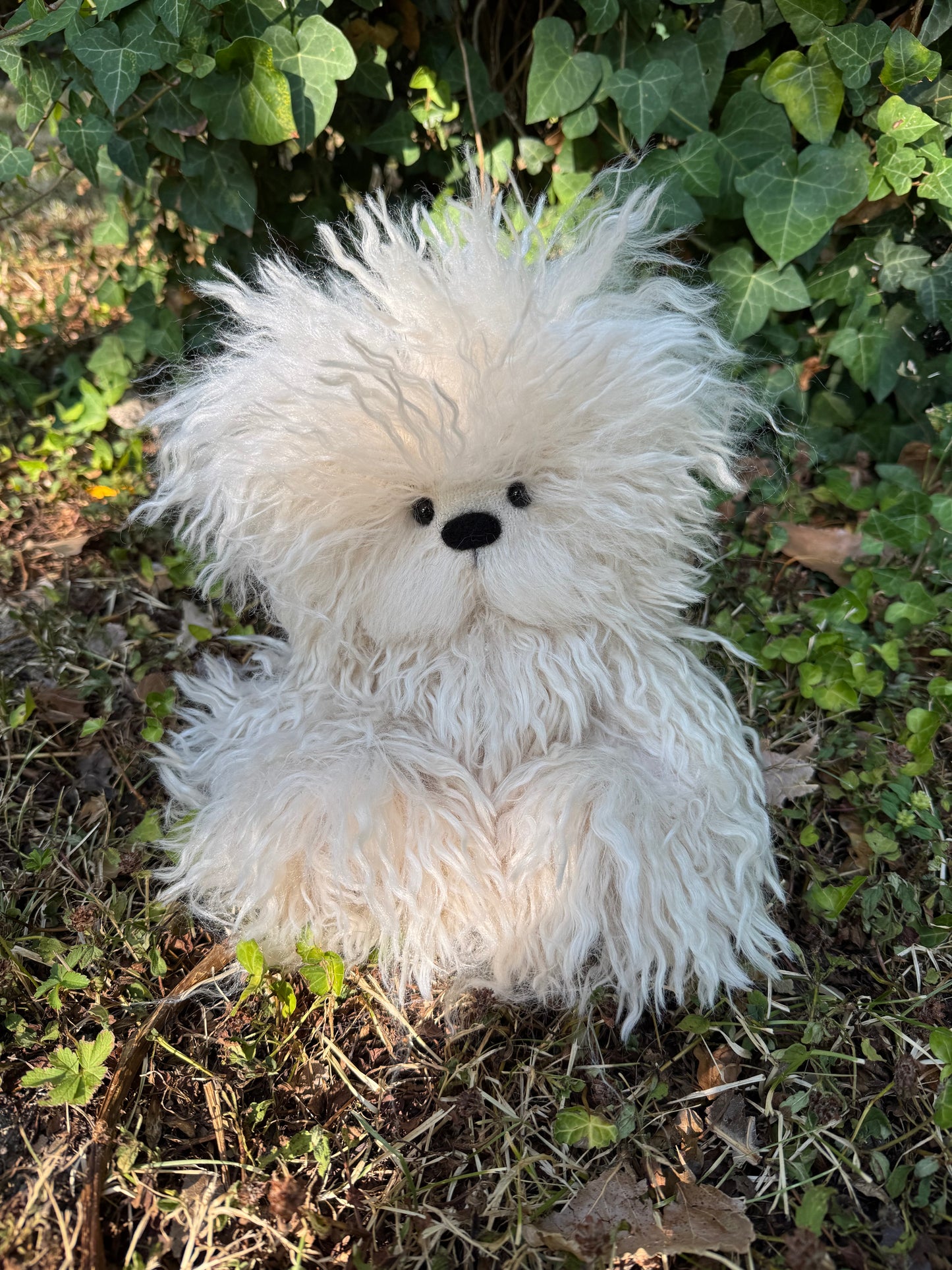 Ours de collection Rasta Bear en fausse fourrure frisée beige, assis dans l’herbe