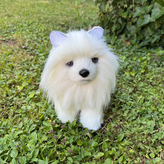 Chien Poméranien en peluche blanche réaliste debout sur l’herbe