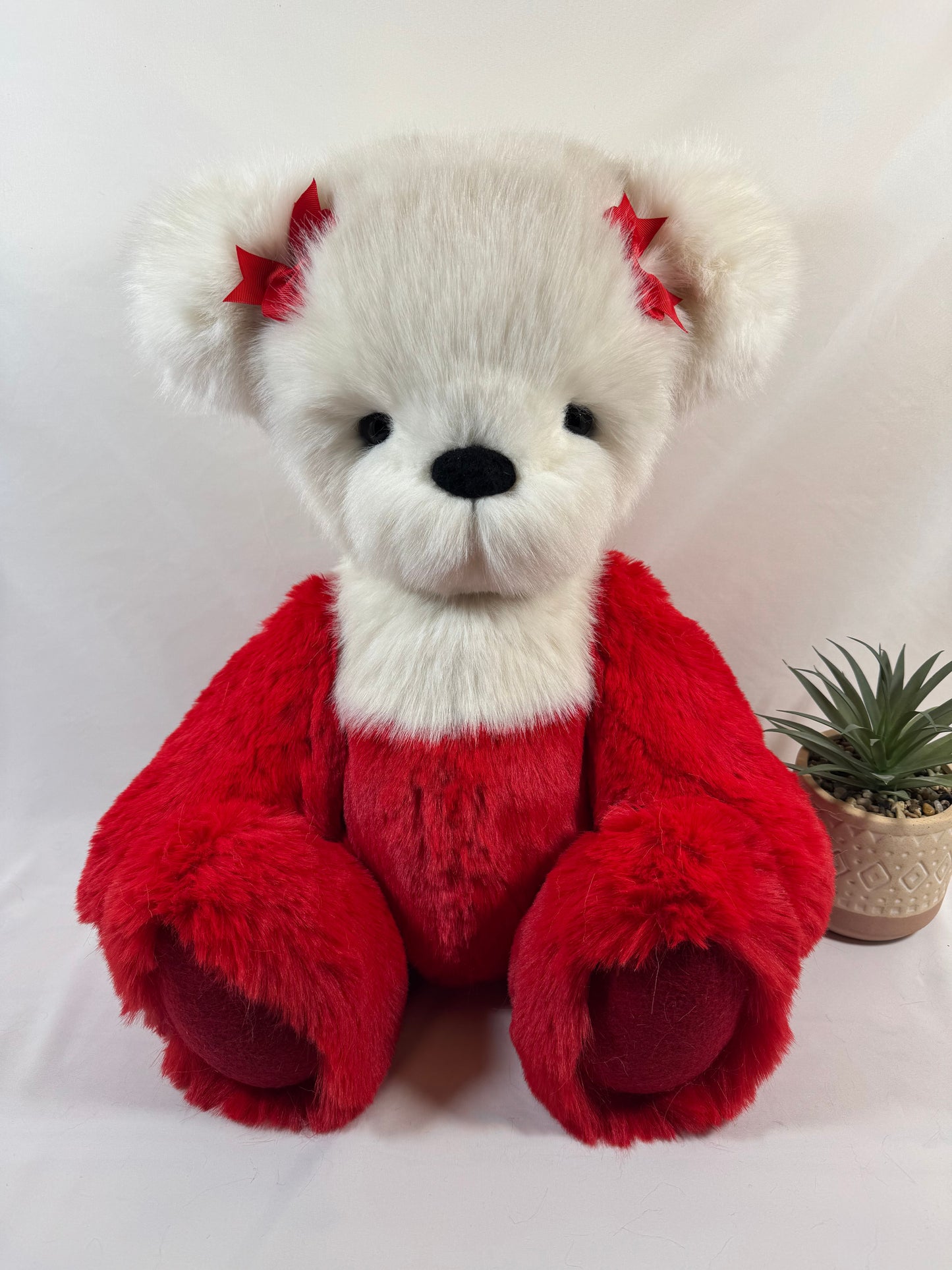 Gros plan du visage de l’ours articulé Pomme d’Amour avec nœud rouge