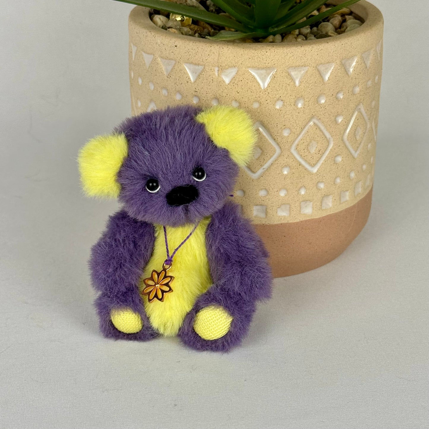 Peluche artisanale articulée à l’ancienne avec médaillon fleur et yeux en verre.