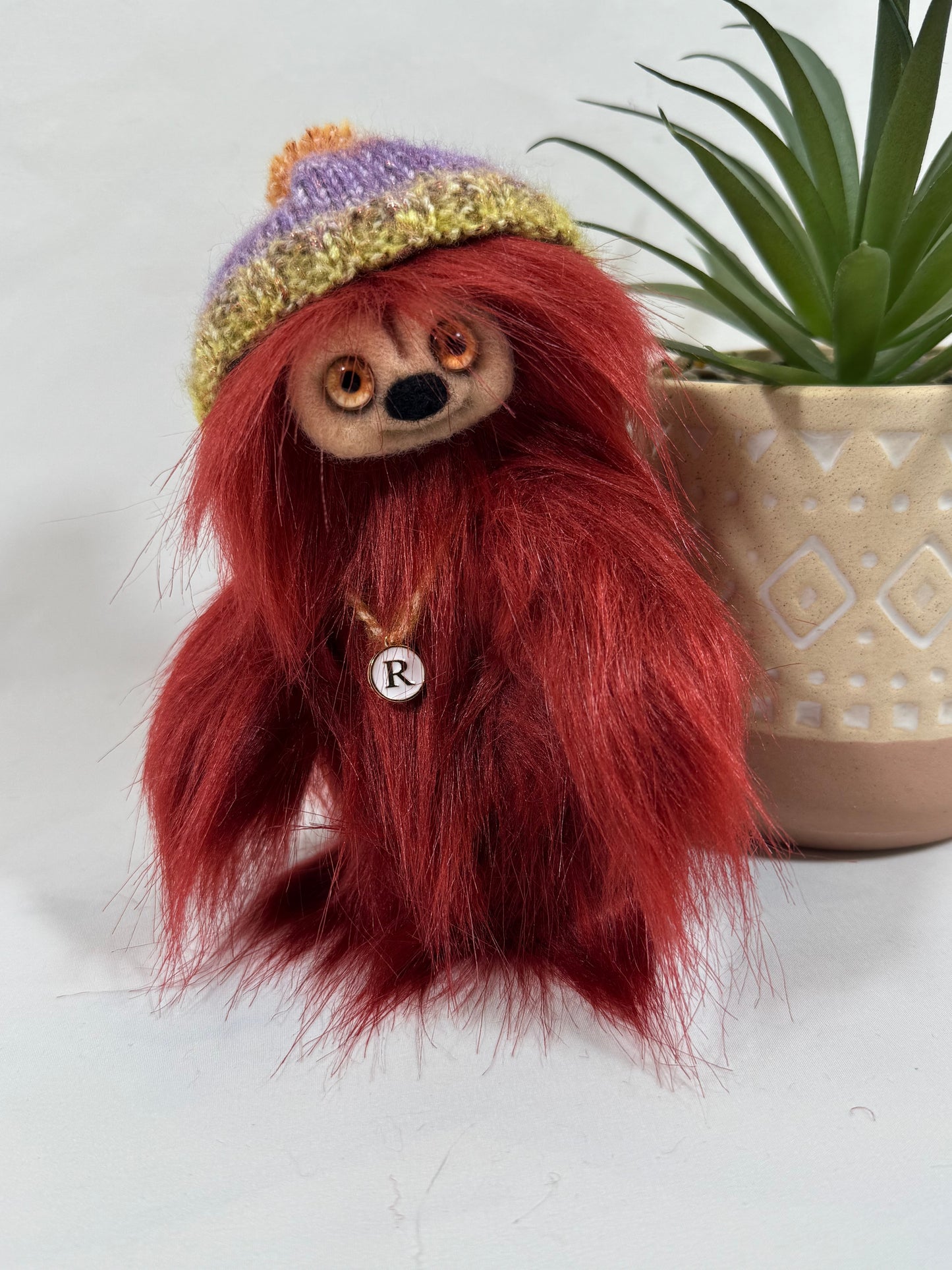 Détail du visage de Roussy, peluche artisanale rouge aux yeux orangés et au nez feutré doux