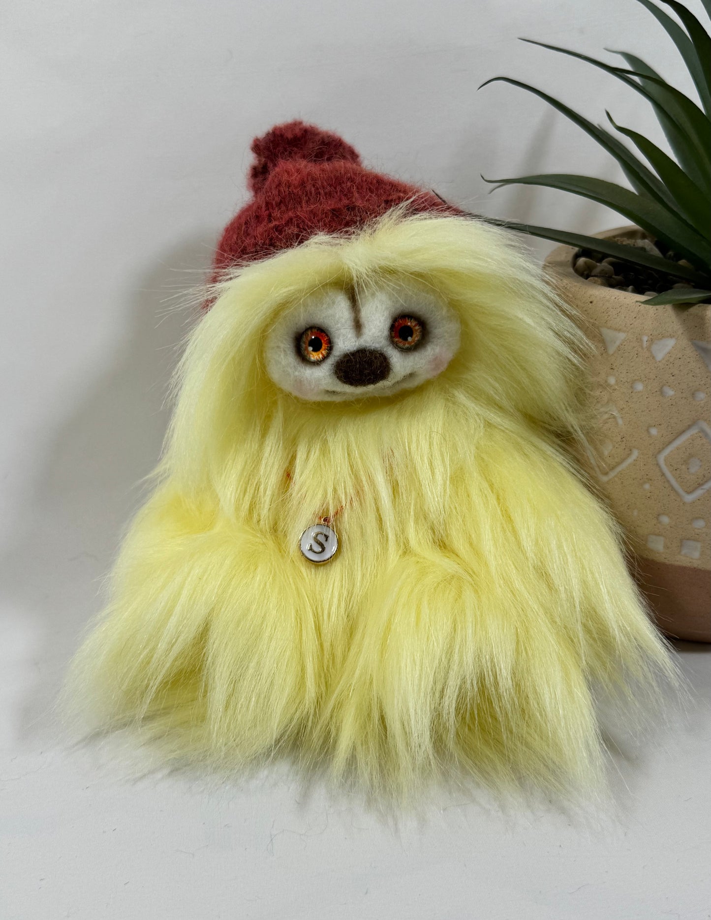 Frimousse Soléa 17 cm en fausse fourrure jaune pâle avec bonnet bordeaux tricoté main et pendentif initial