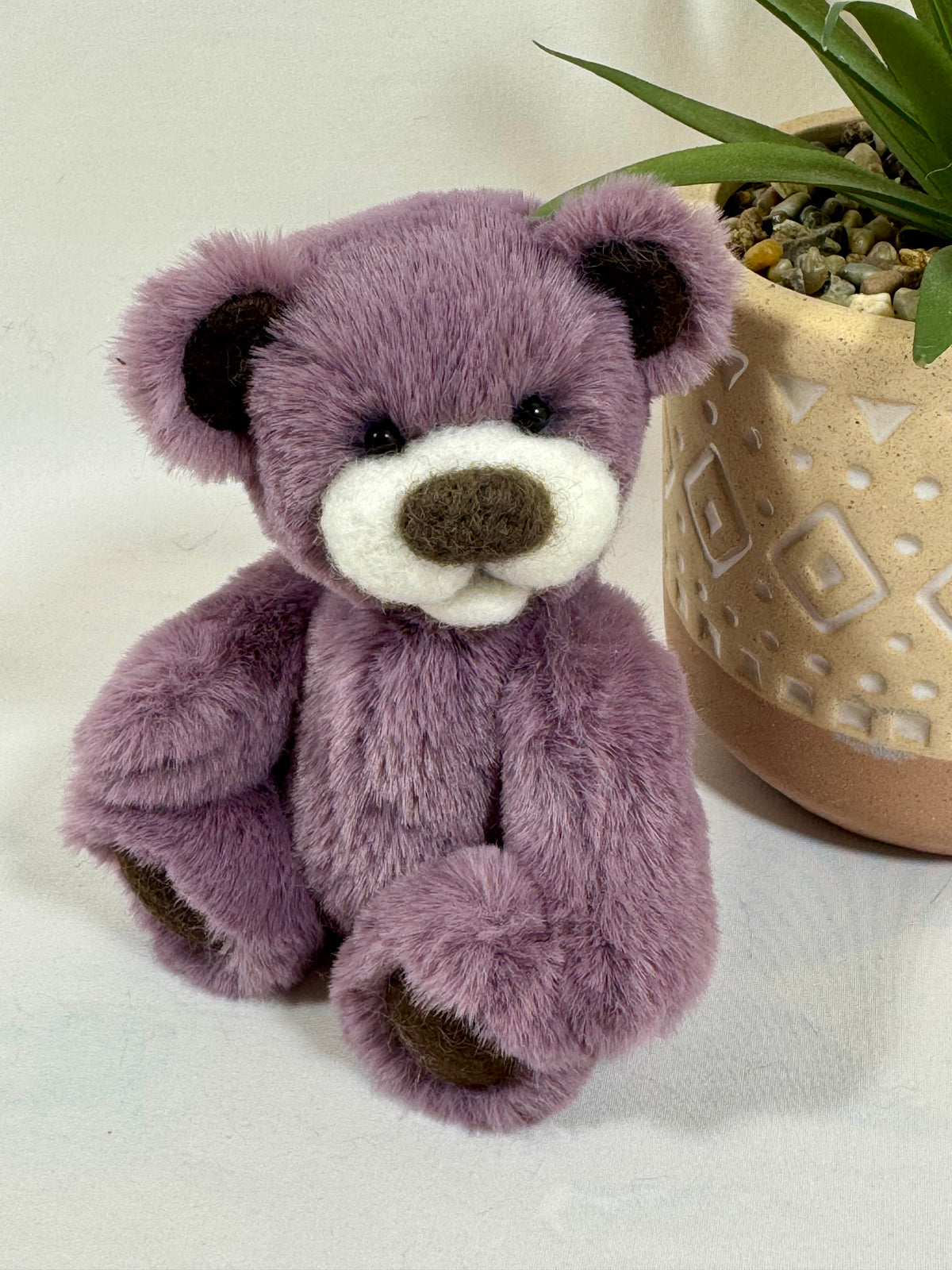 Pimousse, ours de collection articulé de 14 cm en fausse fourrure mauve vieux rose, avec museau blanc en laine feutrée, nez marron et petits yeux noirs.
