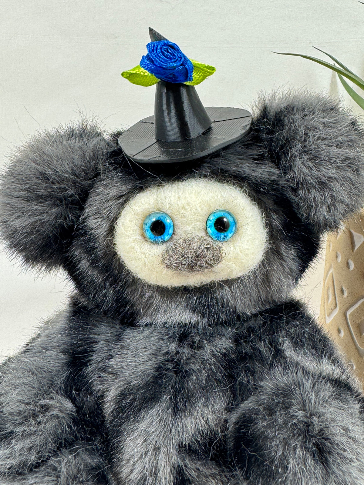 Petite créature de collection Halloween faite main, Gribouillette en fausse fourrure grise aux reflets argentés, grandes oreilles rondes, visage clair et chapeau de sorcière fleuri.