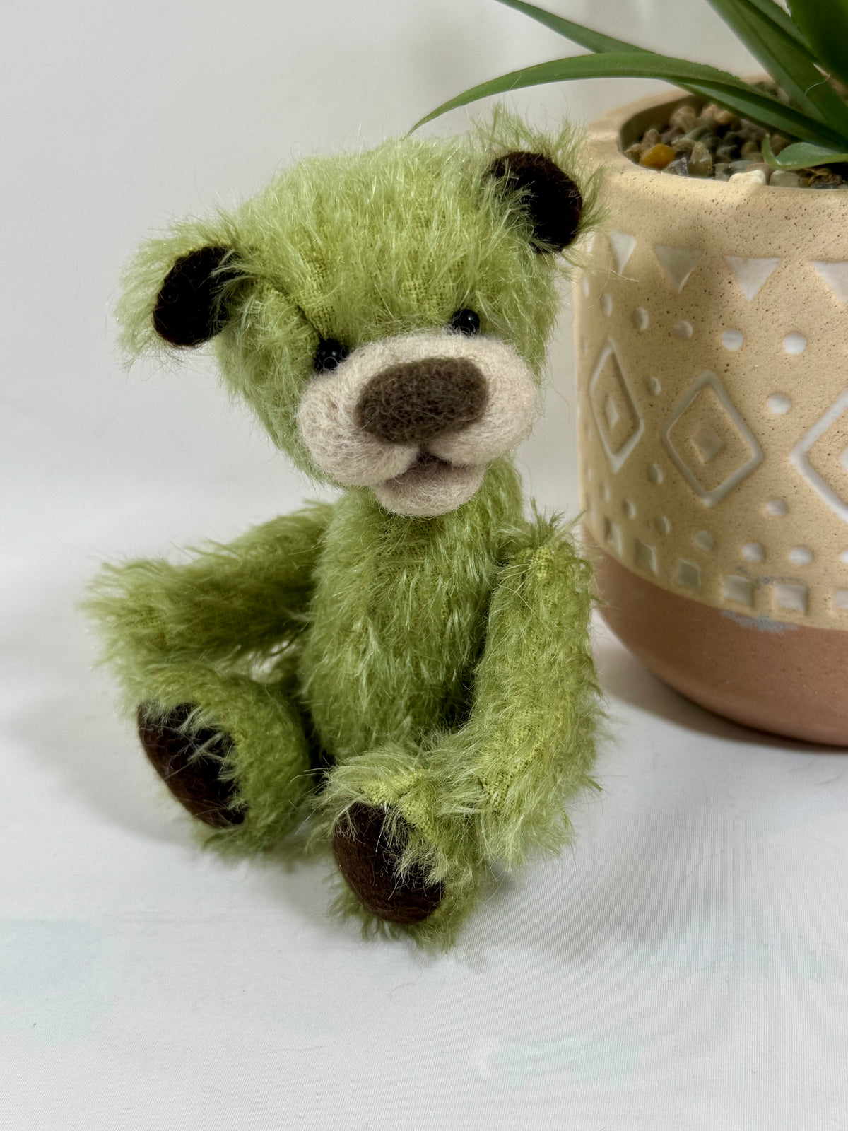 Gros plan sur le visage de Pistache, ours en mohair vintage vert pistache avec oreilles chocolat et museau feutré à la main.