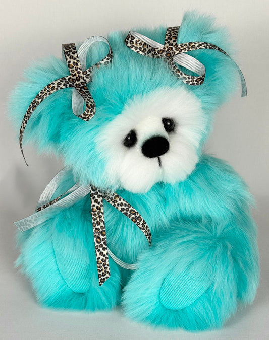 Ourse de collection artisanale nommée Safari, en fausse fourrure longue turquoise et blanche, yeux en verre noir, museau sculpté, décorée de rubans léopard – peluche d’artiste de 30 cm faite main.