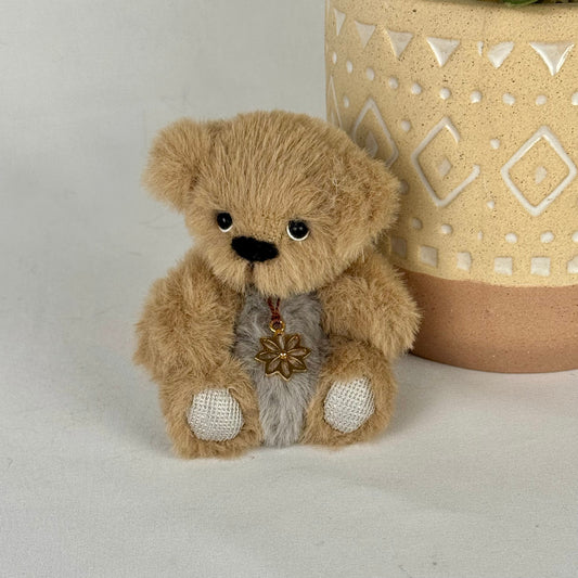 Ours miniature articulé Edelweiss assis devant un pot en céramique, fausse fourrure beige et grise, yeux en verre.