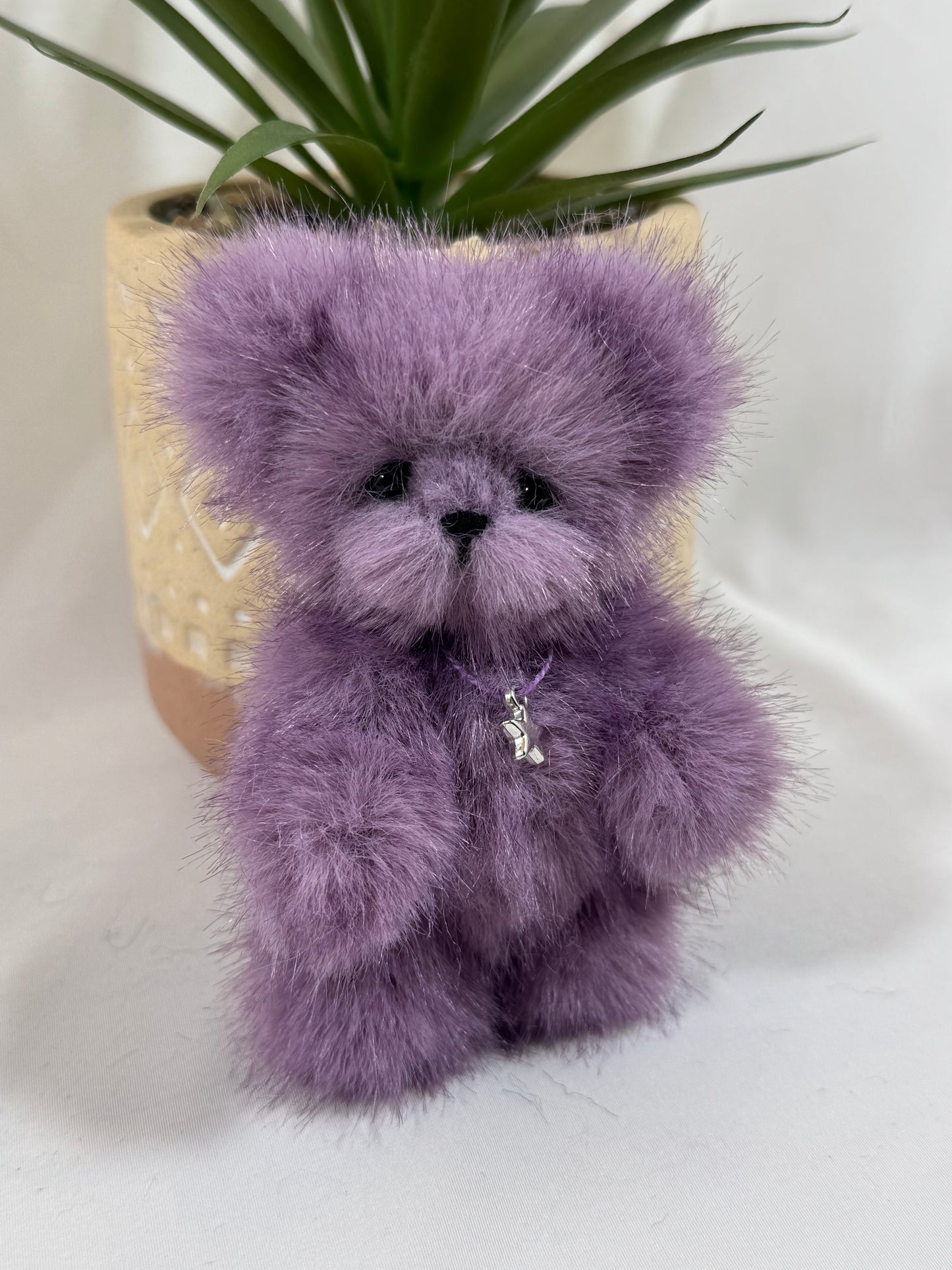 petit ours de collection violet articulé, Stella, posé dans une main.